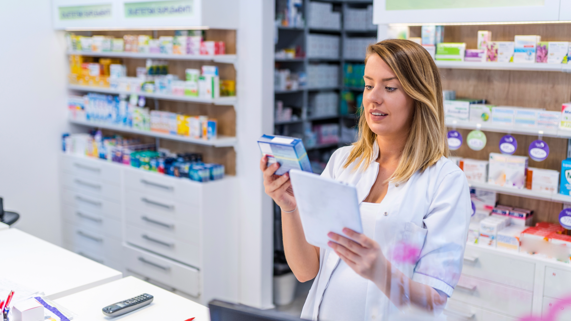 Pharmacist checking a medication box behind the counter of a US retail pharmacy, the largest of the eight pharmacy settings