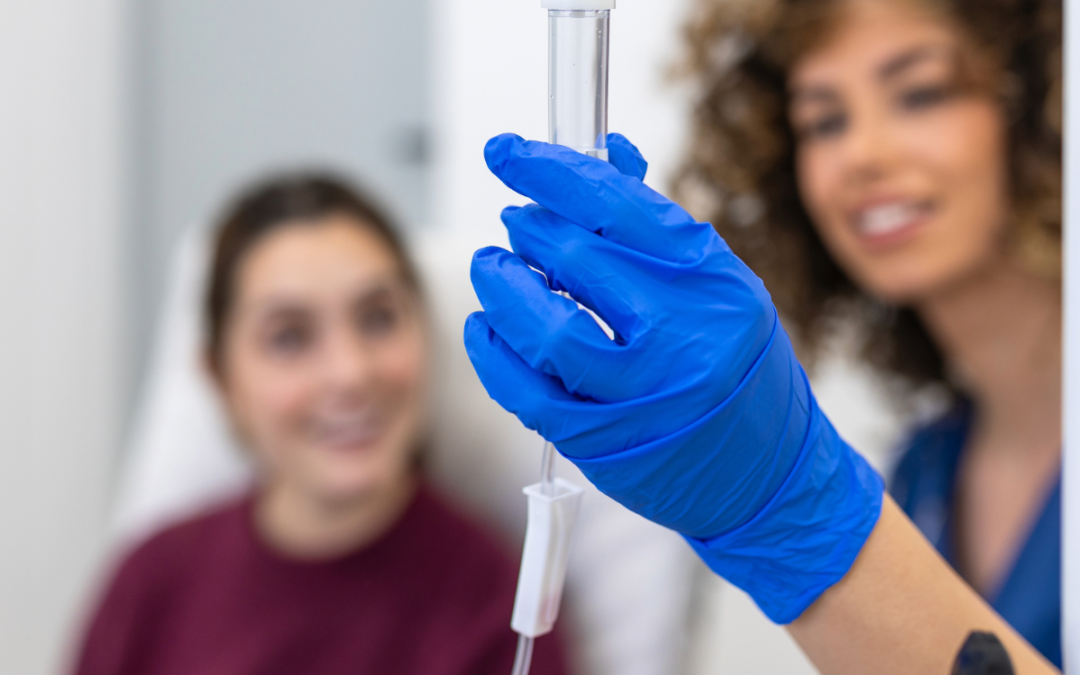 Clinician in gloves setting up an intravenous infusion line for a seated patient